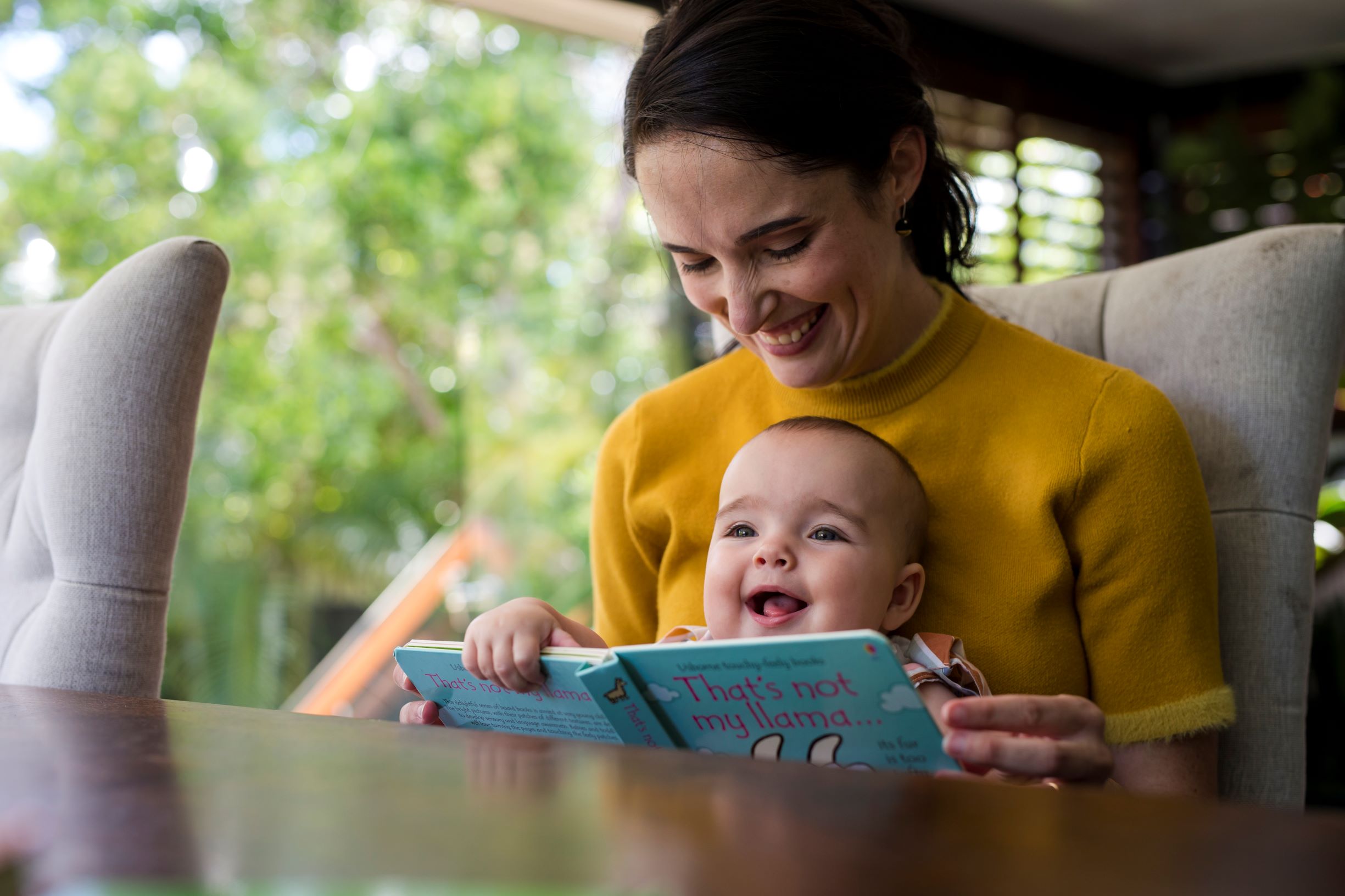 Mother and baby reading a board book inside