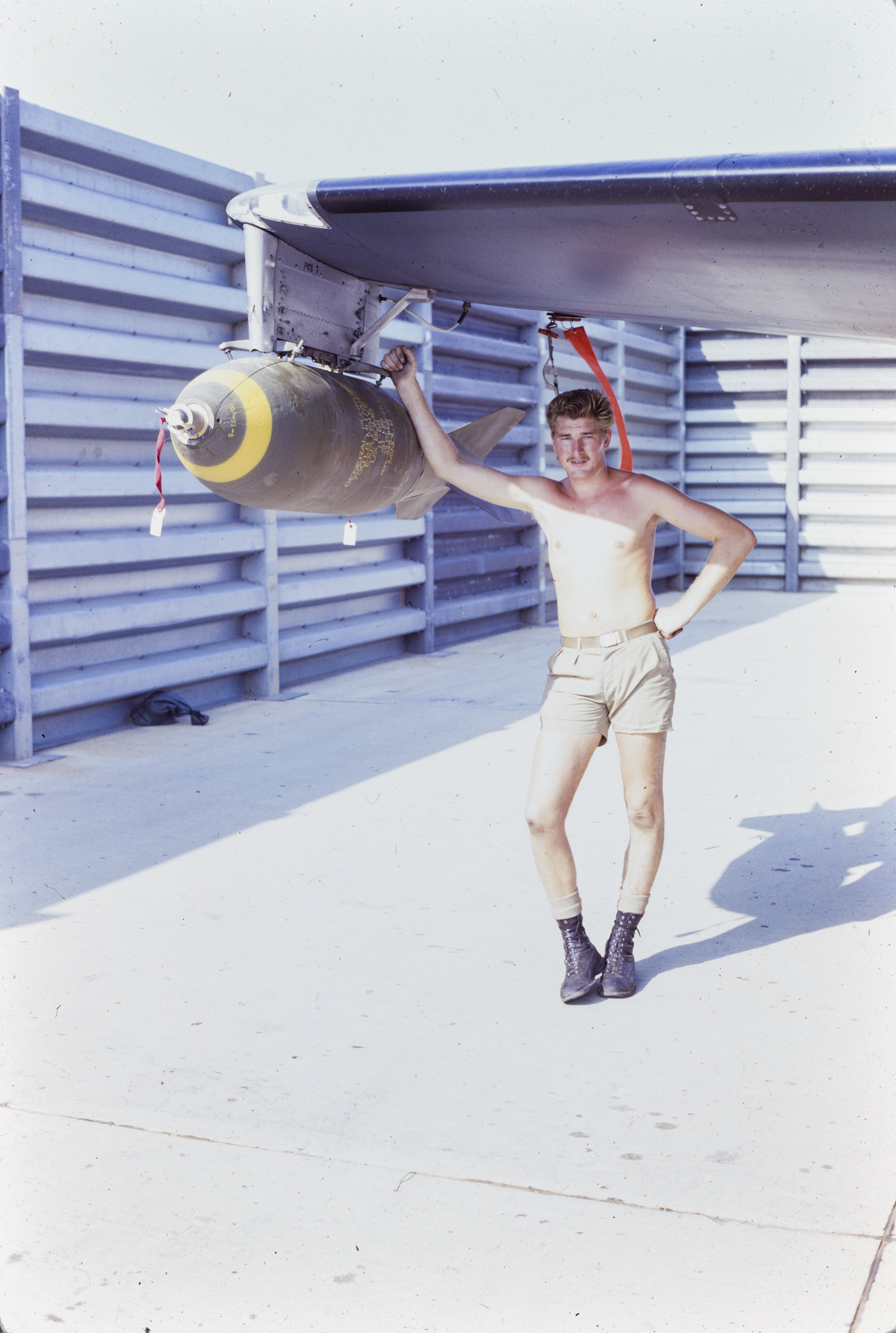 Jon Fallows leans against a mounted bomb on the wing of a Canberra Bomber. 