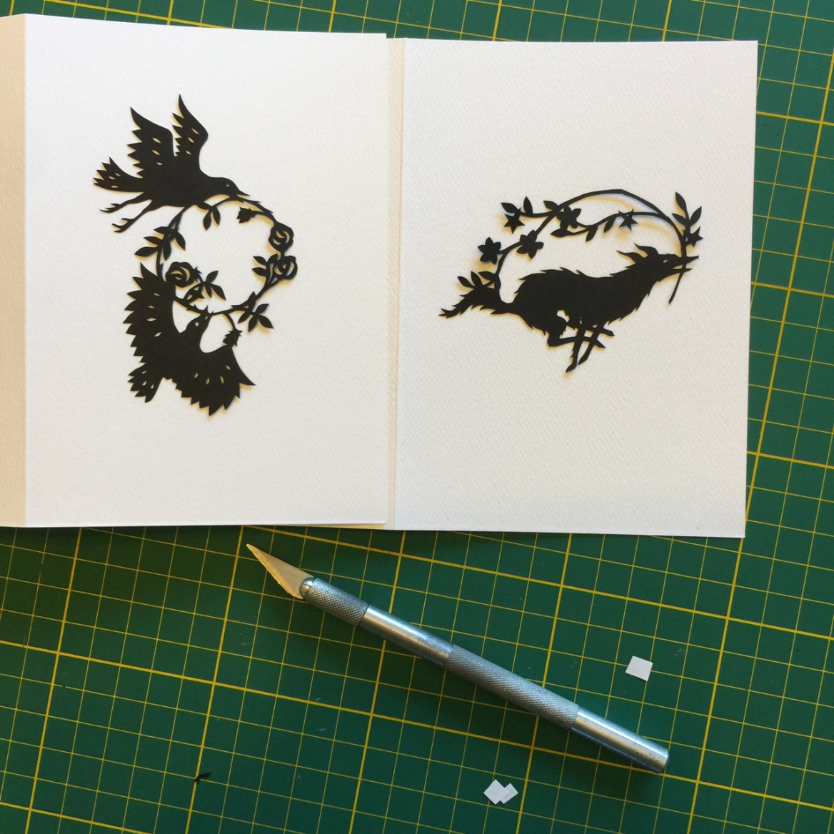 An open sketchbook featuring black cut-outs of birds and wolves