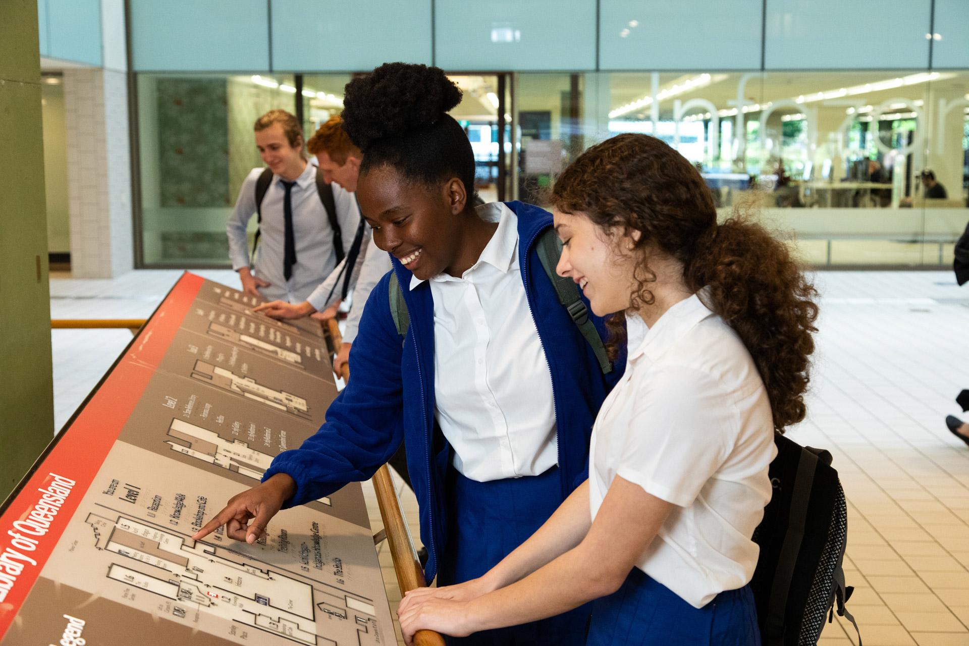 Students pointing and smiling while looking at the State Library map.