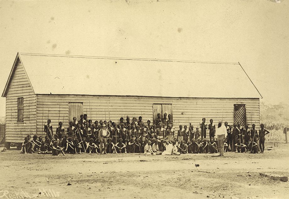 Group of Australian South Sea Islanders standing and sitting in front of a large timber building