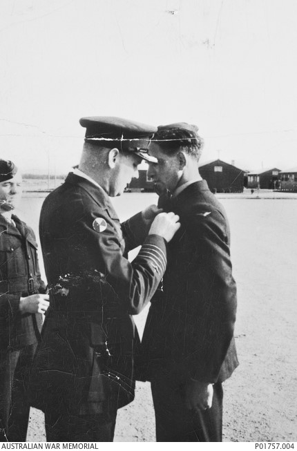 An image of three men in military uniform, one is pinning an award to the collar of the other