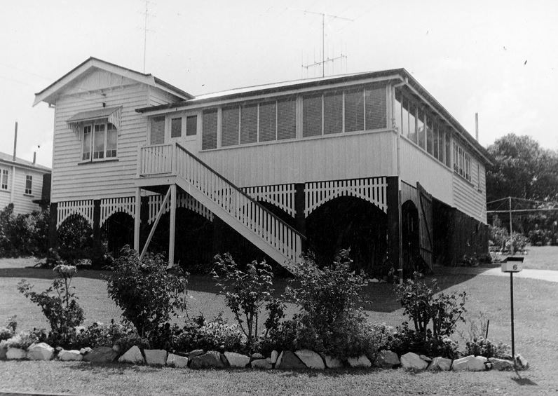 B&W picture of a Queenslander style house with garden bed in front