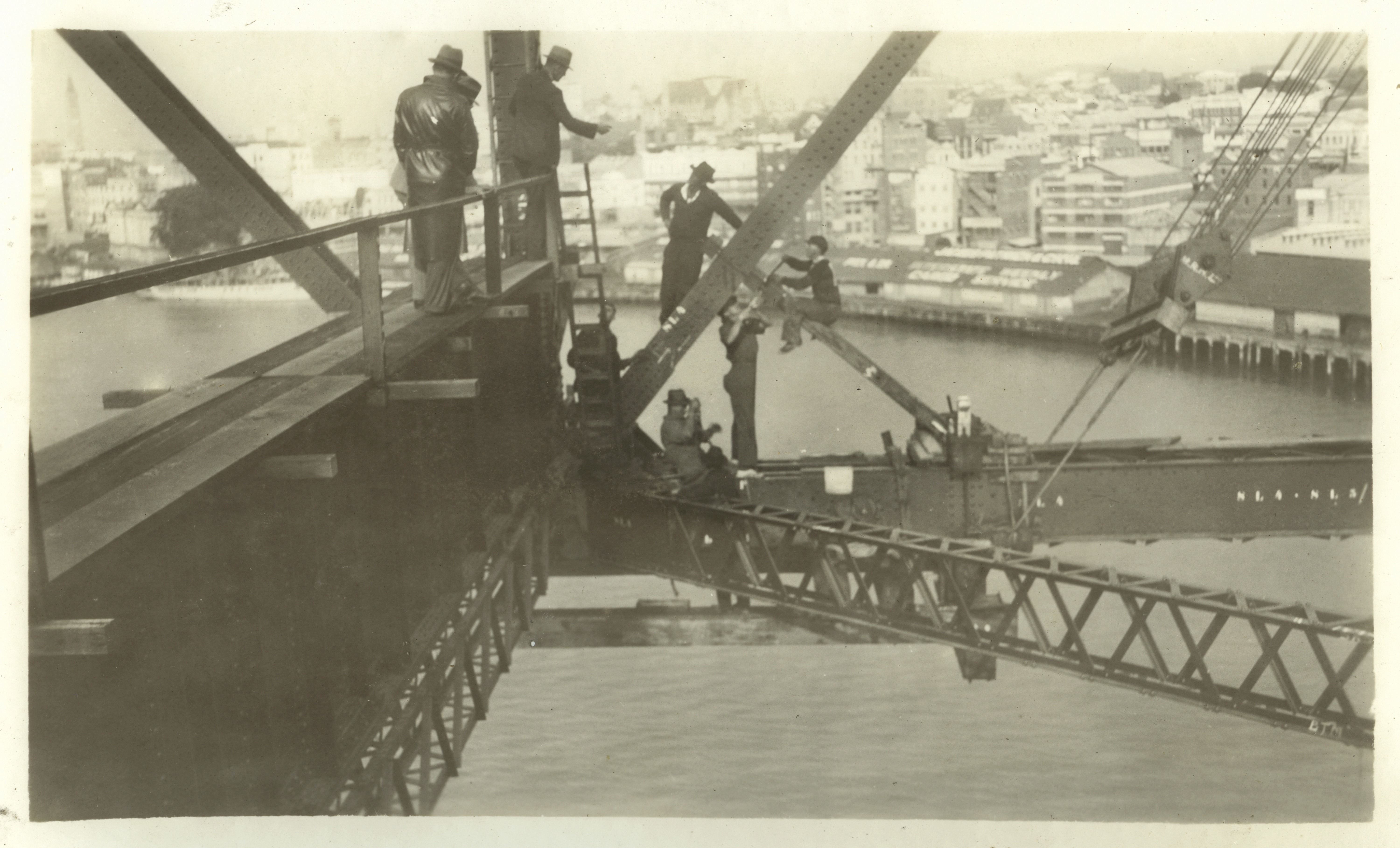 Sepia toned photo taken from the steel support beams of the Storey Bridge, picturing riggers high above the Brisbane River
