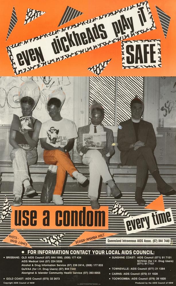 Poster reading: Even dickheads play it safe. Use a condom every time. Poster shows a photograph of four males sitting on a bench at a train station, all wearing condoms on their heads. Telephone numbers are at the bottom for regional and metropolitan areas in Queensland who provide further information on AIDS.