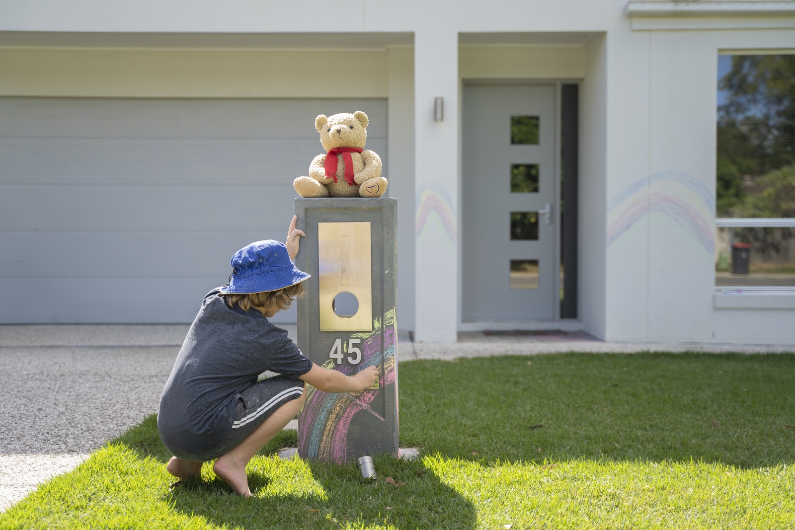 Young boy draws a chalk rainbow on a letterbox at Ferny Grove during the Covid-19 pandemic, April 2020.
