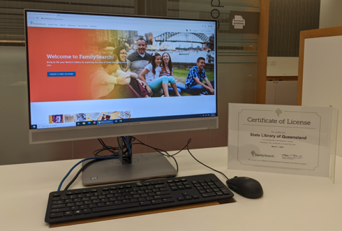 Computer screen displaying home page for FamilySearch with affliate certificate on table on right.