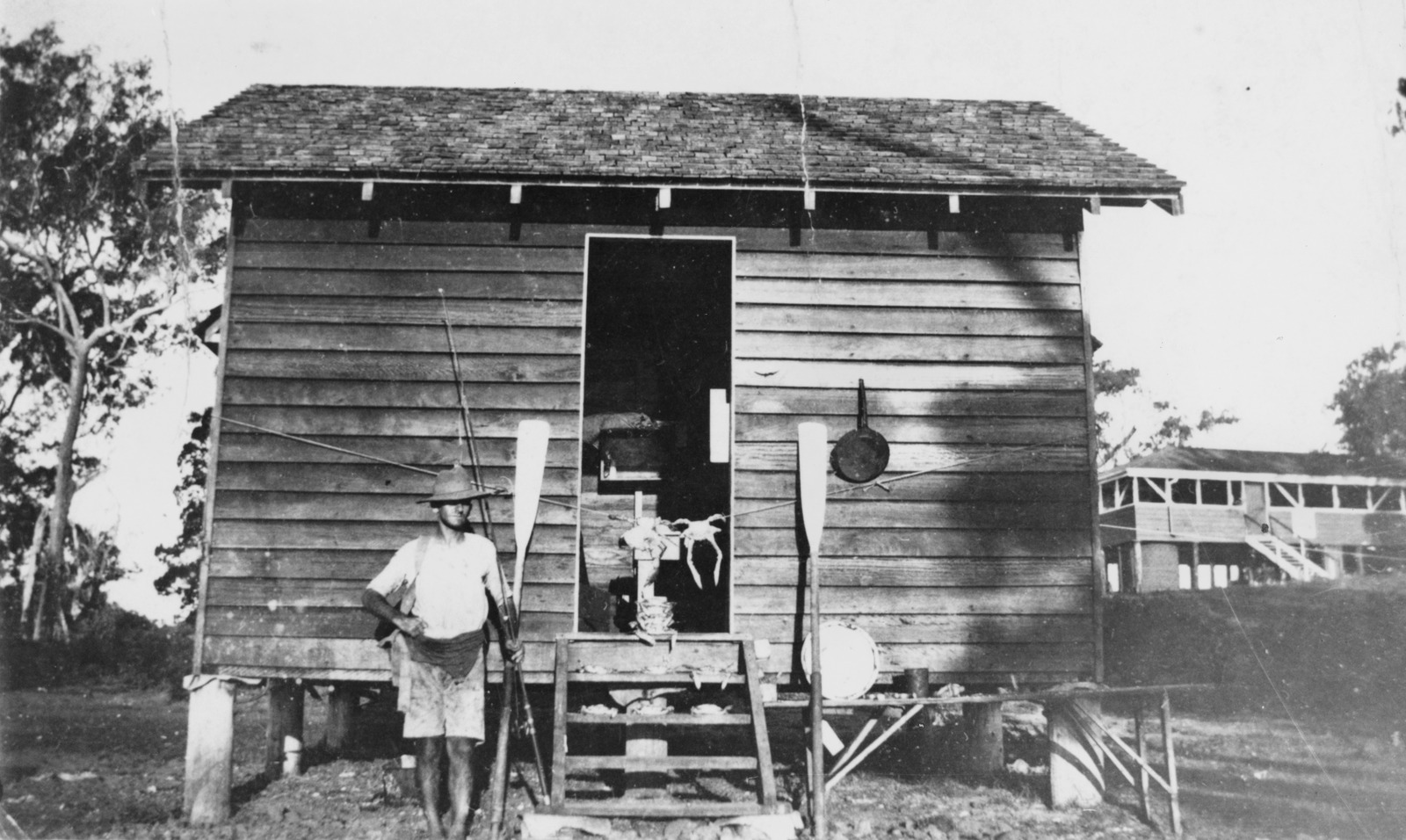 Fisherman standing outside a fishing shack at Bribie Island, ca. 1925