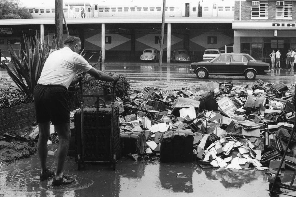 A staff member empties a wicker basket on a trolley that had been filled with flood damaged books and other debris from the State Library of Queensland building in South Brisbane.