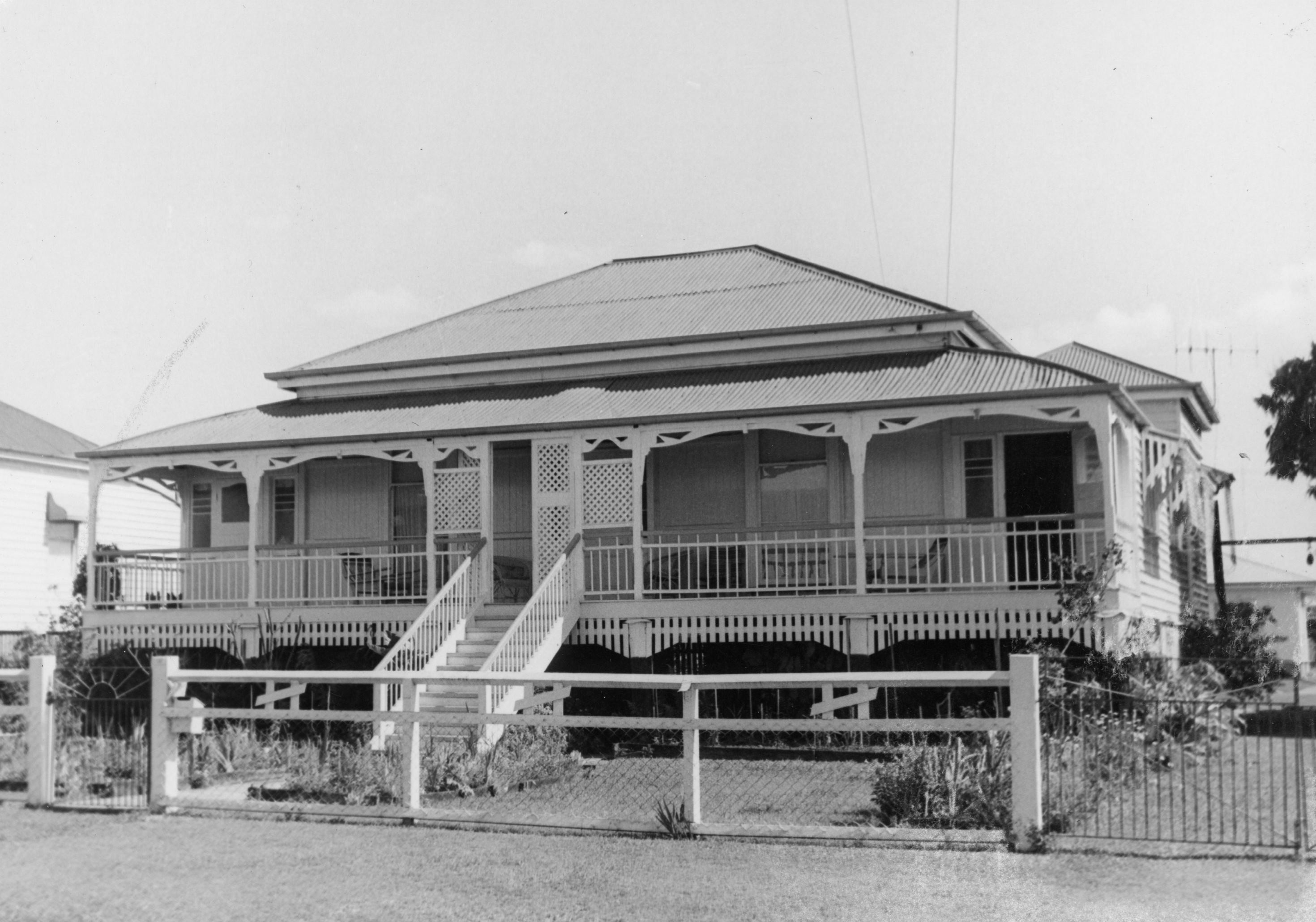 B&W image of single storey, weatherboard house with a corrugated iron roof and a chain link and timber fence at Maryborough.