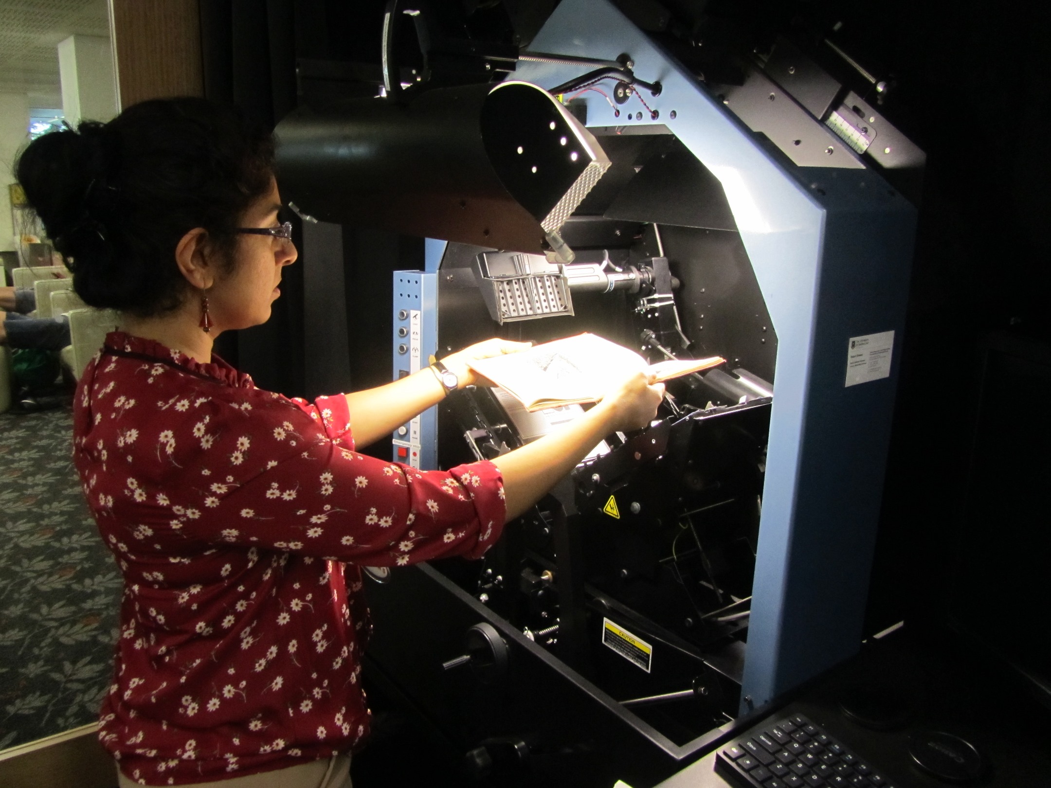 State Library of Queensland Reformatting team staff member digitising items with the Kirtas bookscaner