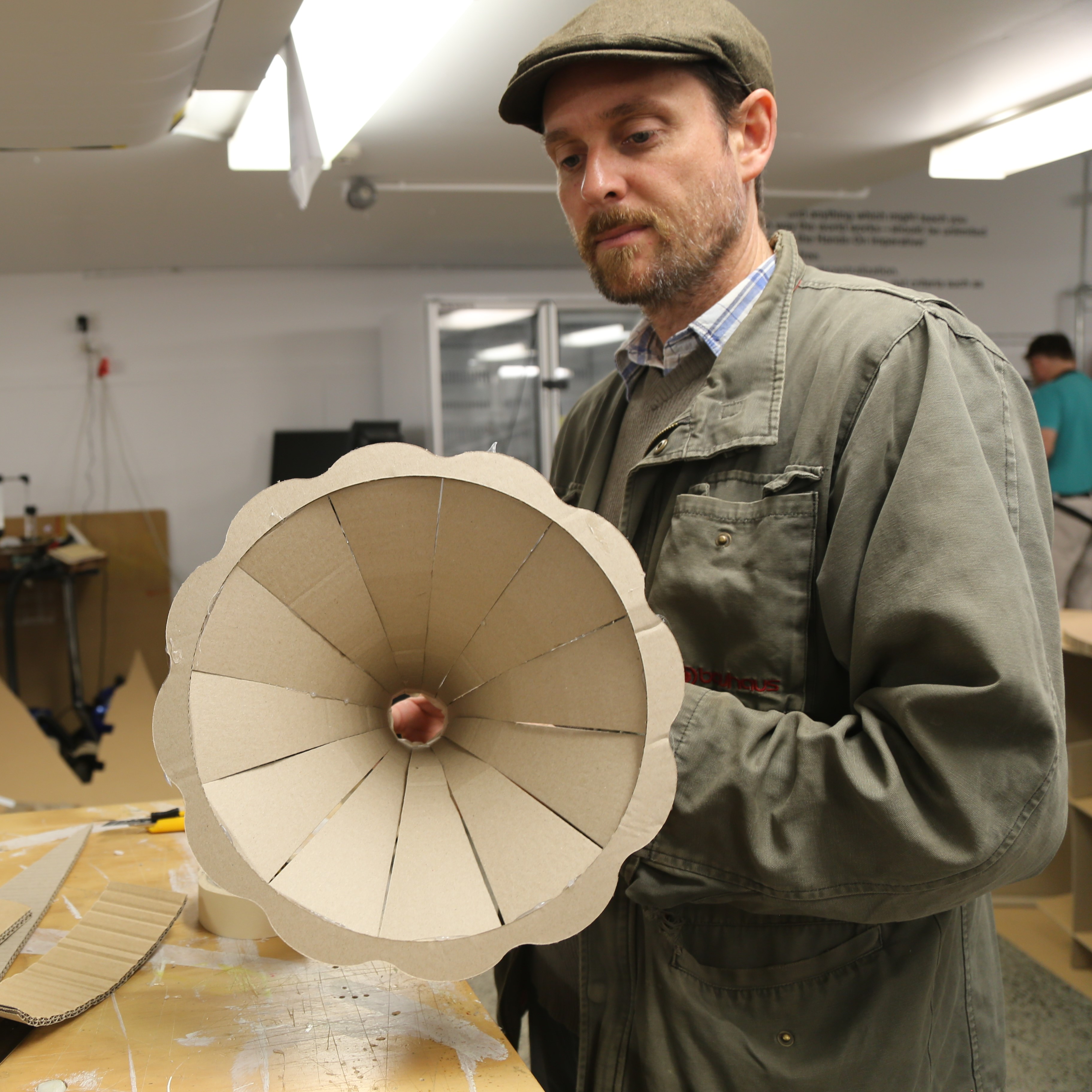 Man holding fluted cardboard gramophone horn.
