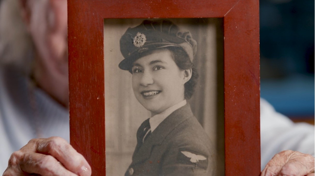 Jackie McLaughlin holding a photograph of herself when she enlisted in the British Women’s Auxiliary Air Force.
