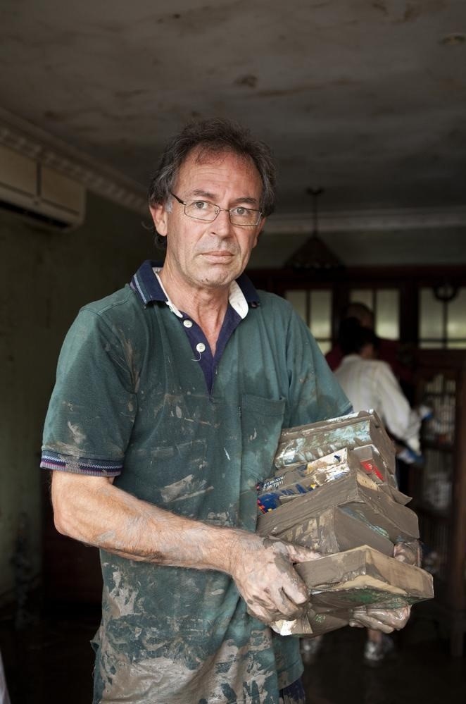 John Bellas carrying ruined books in his flooded home at Fairfield, 2011