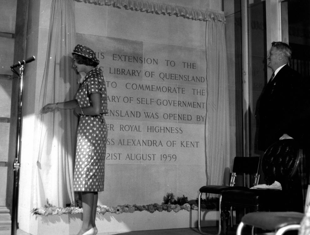 Princess Alexandra, wearing a polka dot dress with a short jacket and hat made from the same material, unveils a plaque to officially open the extension to the Public Library of Queensland (later the State Library). Queensland's Premier, George Francis Reuben 'Frank' Nicklin observes the ceremony from one side of the commemorative plaque.