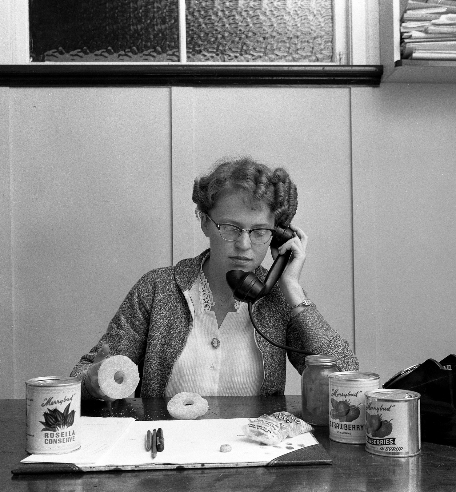 woman sits at a desk surrounded by cans of jam and ginger 