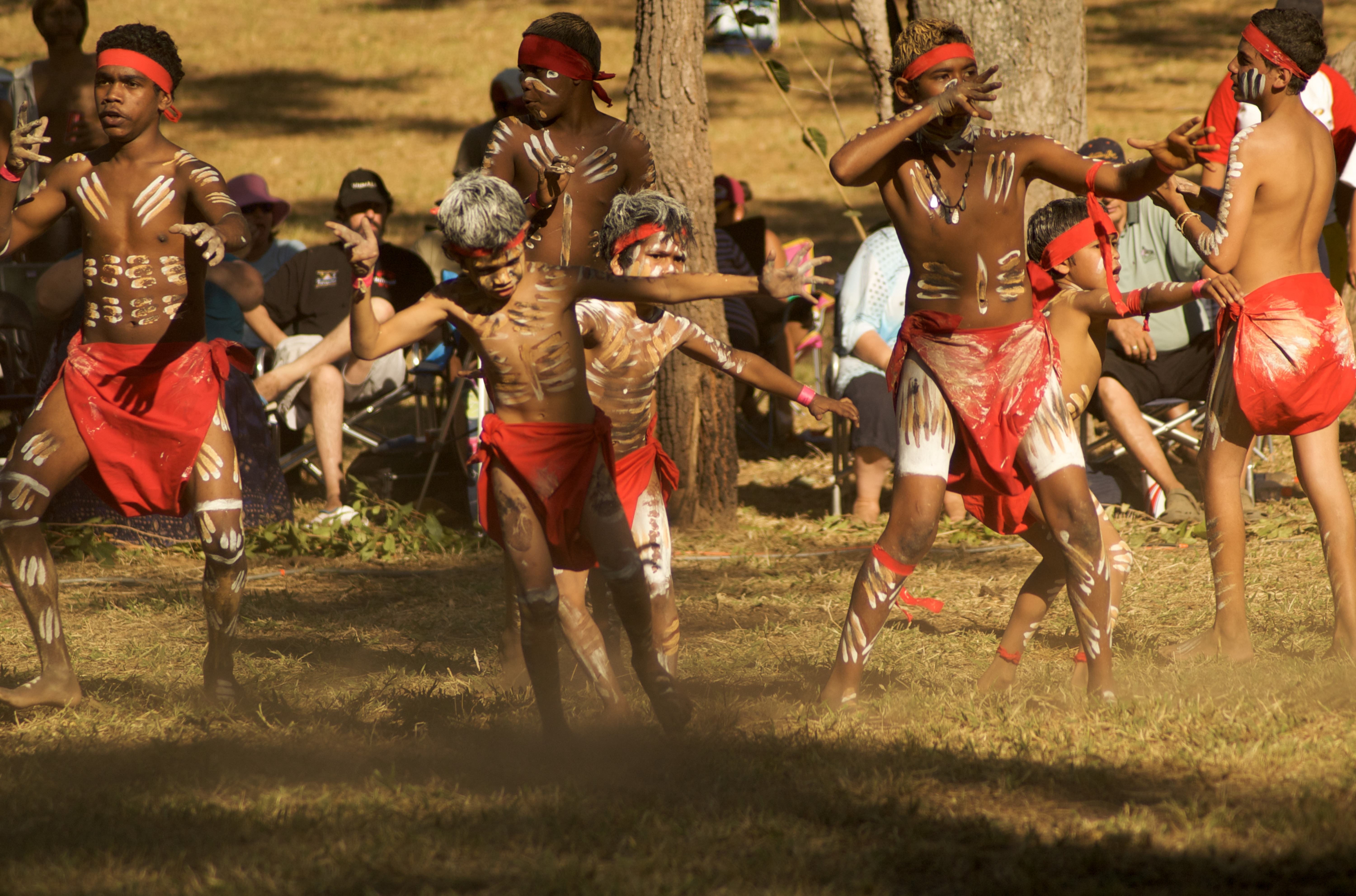 Boys performing an aboriginal dance on dry grass