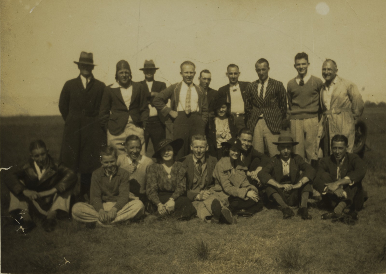 A group of people pose for a photo in a field. The photo is black and white from 1936.