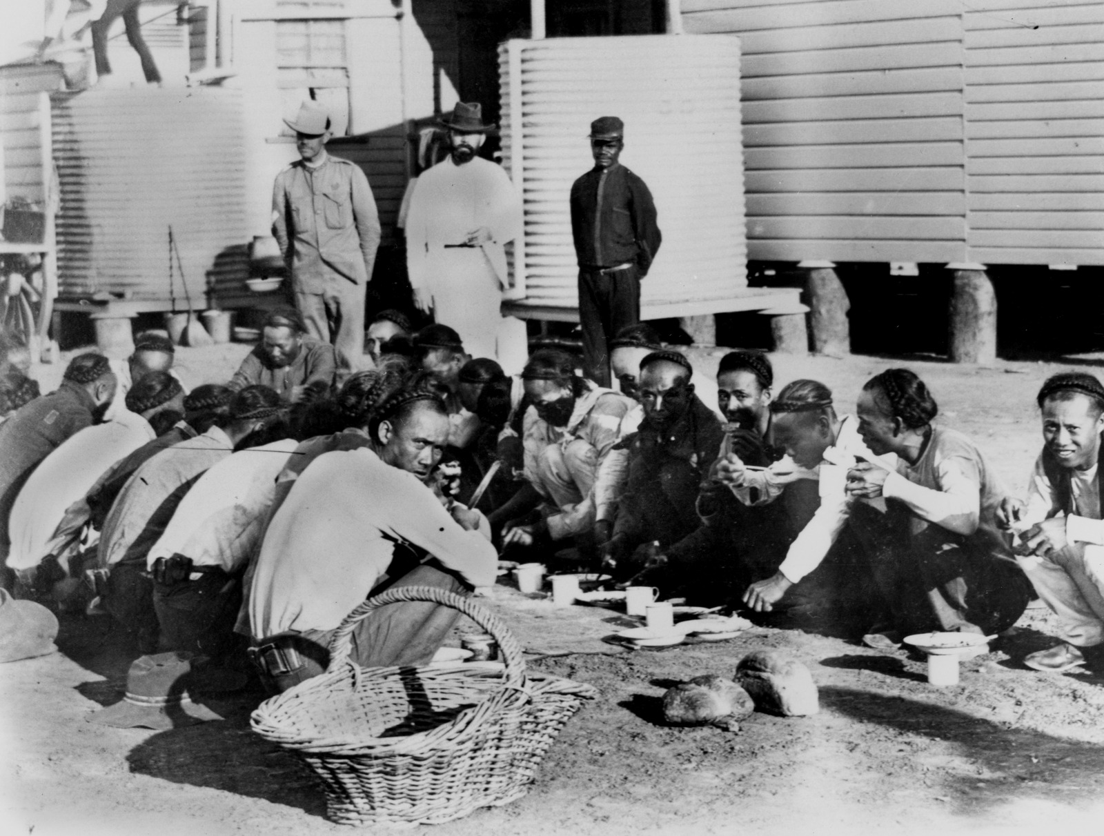 Chinese prisoners being fed under supervision outside in the Goal Yard, Burketown, Queensland, ca. October 1900.