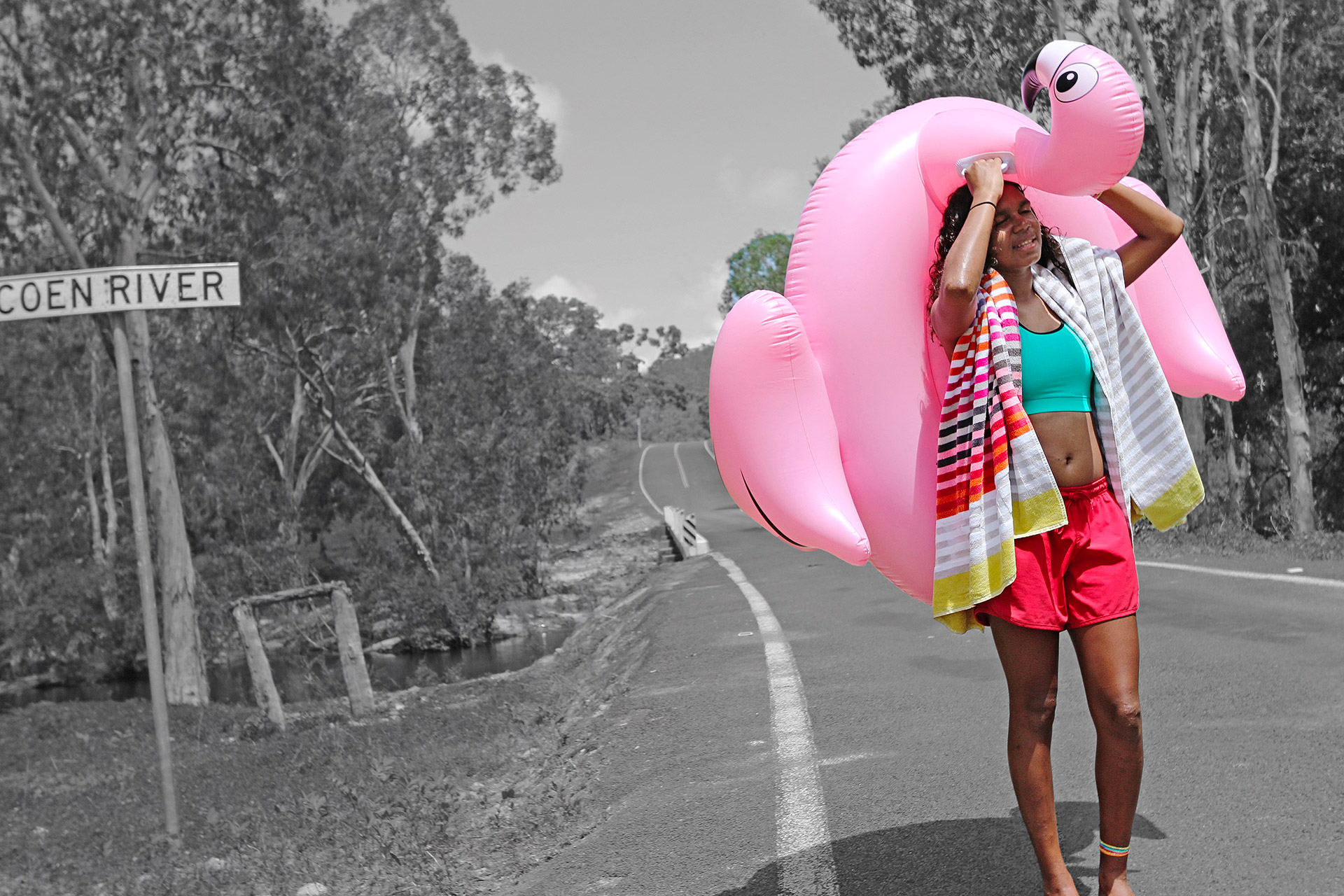 Girl walking down the street carrying an inflatable flamingo