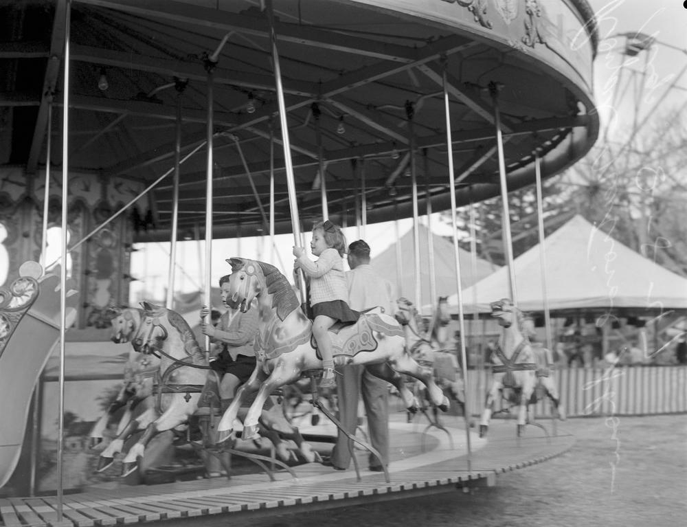 Children ride a carousel at the Brisbane Exhibition, 1947. John Oxley Library, State Library of Queensland. Image 28118-0001-1383