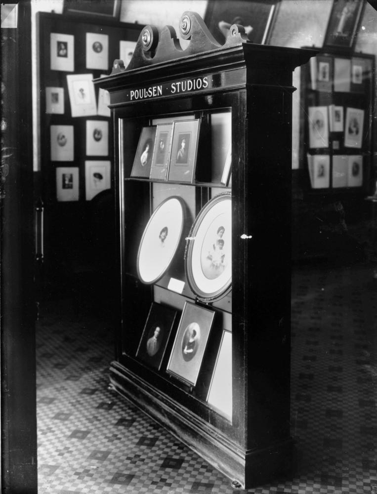 black and white image of a cabinet with portraits inside 