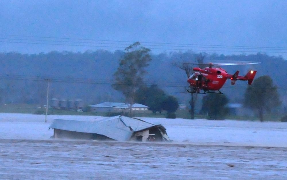 N.S.W. Rural Fire Service helicopter flying over a collapsing house during the floods in Grantham, Queensland, 2011