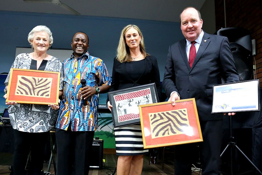 Rose Swadling, Lawrence Chitura and Karen Morris show examples of art and Bruce Young MP holds a Certificate of Appreciation