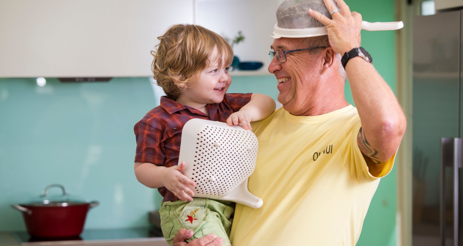 Child and grandfather playing in the kitchen