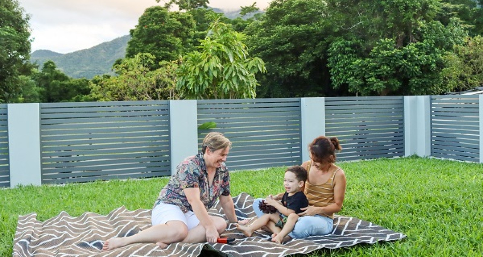 Women and child on a rug in backyard