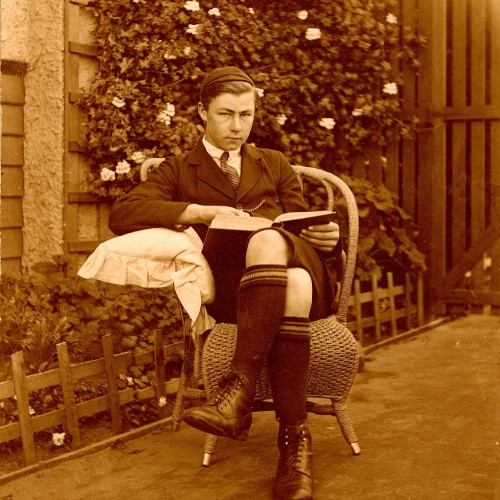 Teenage boy reading a book in the garden, 1910-1920