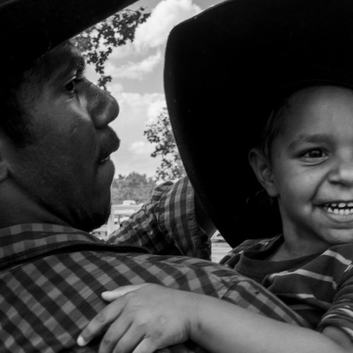 Man holding a child wearing a wide brimmed hat.