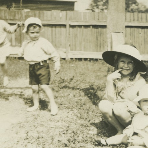 Black and white photograph of rour small children in a suburban backyard.