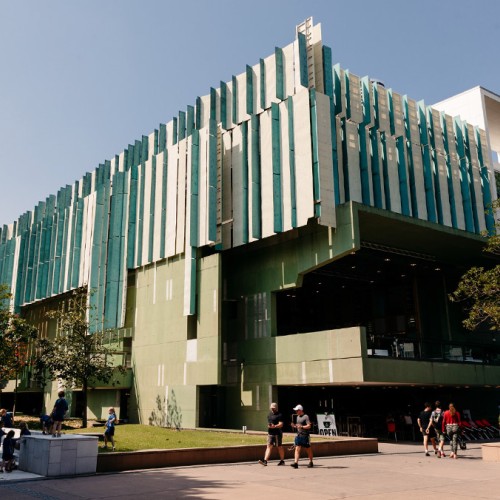 Exterior view of State Library building during the day with people walking in front of it. 