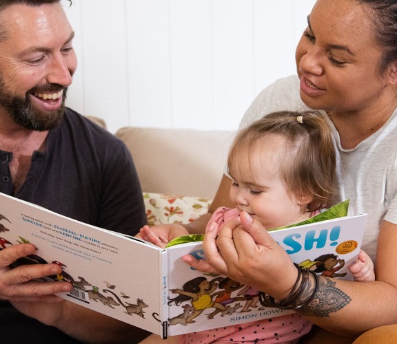 Family reading to small child at home