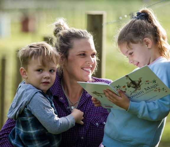 Mother and children on farm reading a book