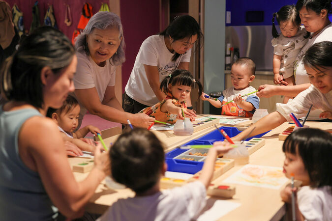 A group of parents and young children painting together.