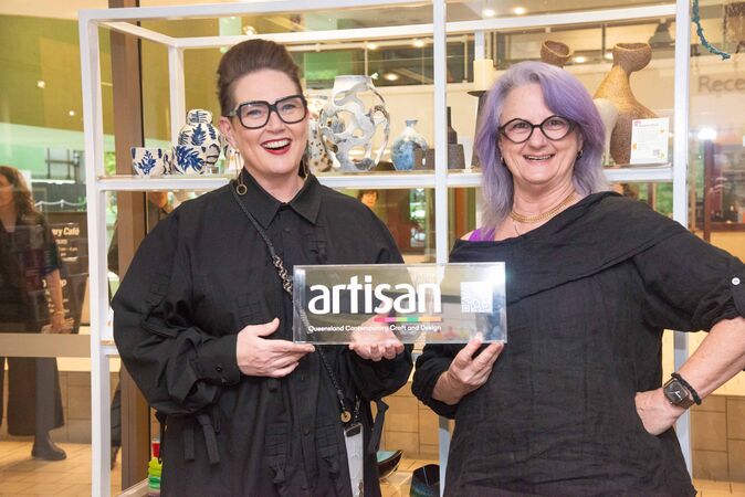 Two women holding a sign that says artisan