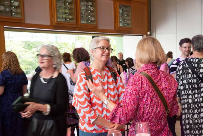 Two women in conversation in crowd at social event
