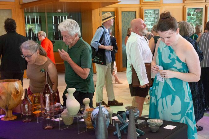 Group of people looking at ceramics and craft work on display