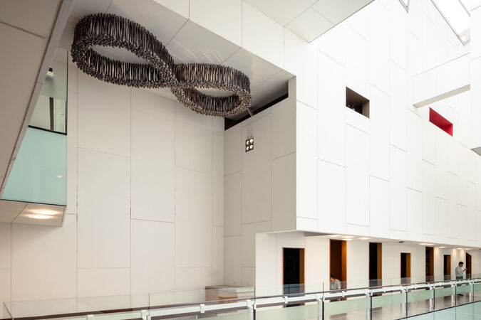 A wide angle view of the entire artwork "Black Opium" by Fiona Foley, including a large aluminium figure 8 plus 7 small rooms