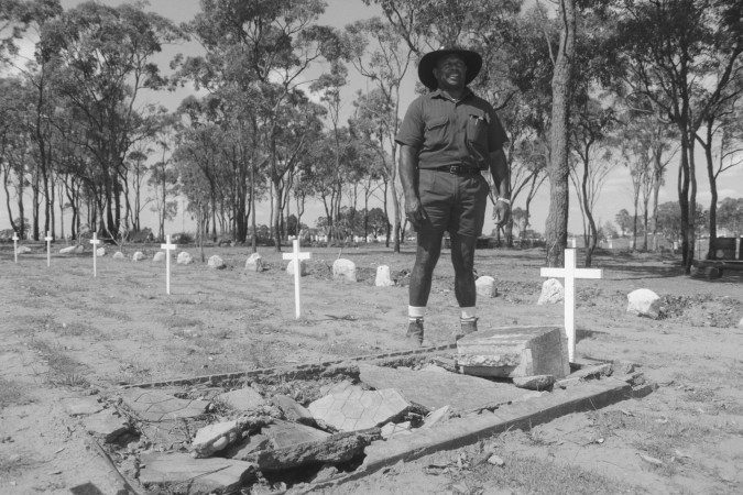 Danny Tanner standing next to an Australian South Sea Islander grave at the Bundaberg Cemetery, Queensland, 2000.