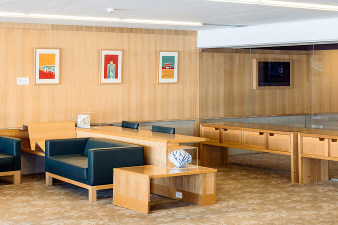 Three brightly coloured, framed pictures on a timber wall surrounded by couches and tables