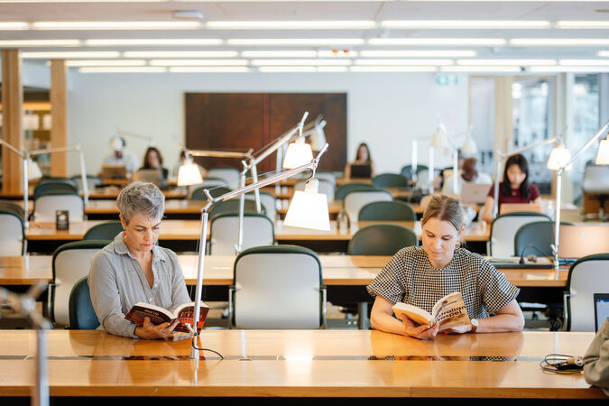 Interior of a library with people writing and reading at desks