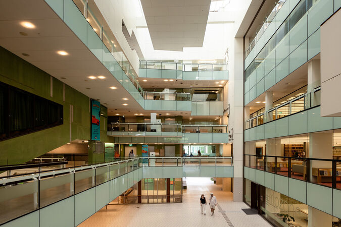 View of a bright atrium inside a library showing balconies and people moving through the space