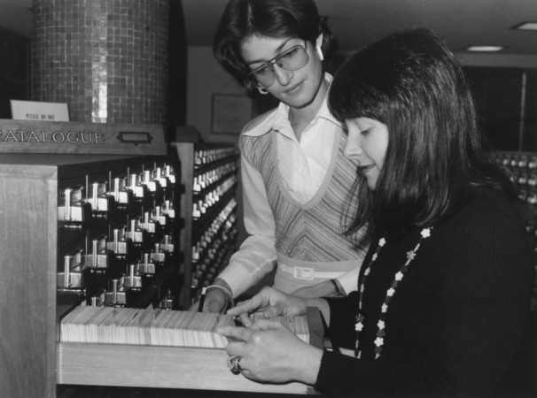 Black and white photograph of two women flicking through the card catalogue at the State Library.