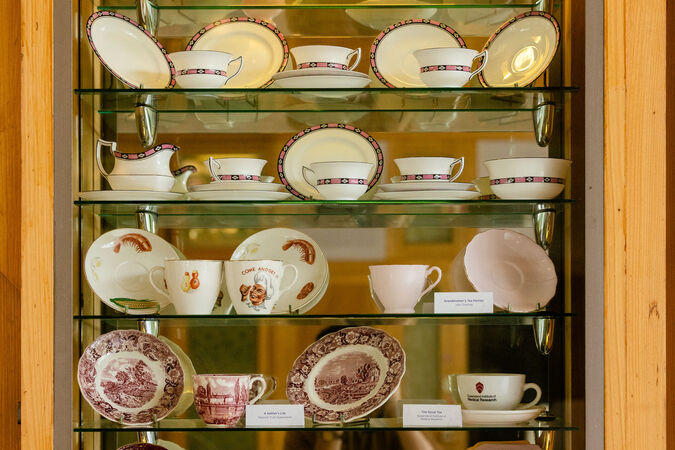 Tea sets on glass shelves in a cabinet