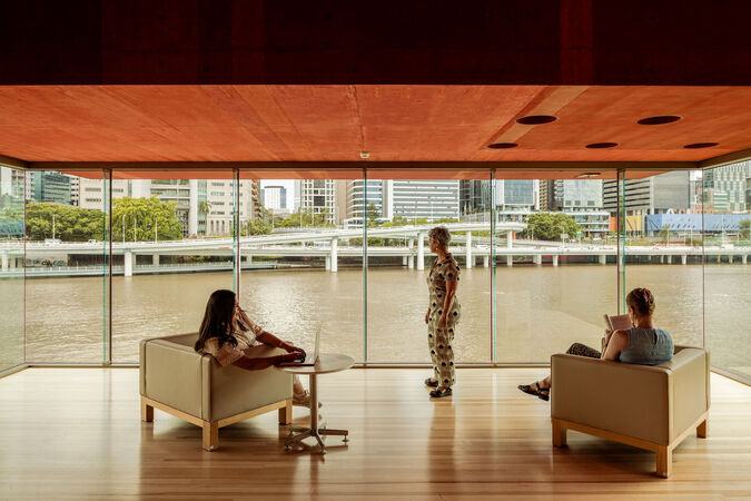 Red Box at State Library of Queensland; timber floors, people on couches, a wall of glass overlooking the river