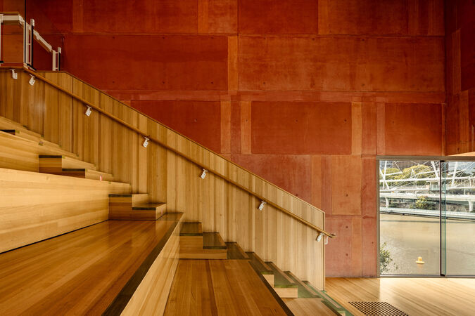 Red Box at State Library of Queensland; there are timber stairs and floors and a red wall overlooking the river