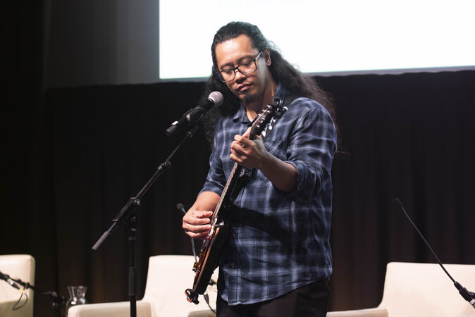 2025 Letty Katts Fellow, Dr Carl Anacin singing and playing a guitar at Research Reveals